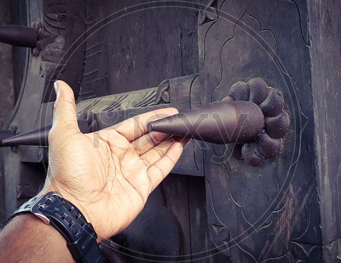 A man's hand touching a big metal spike installed on a fort's door to prevent enemy elephants from pushing against it