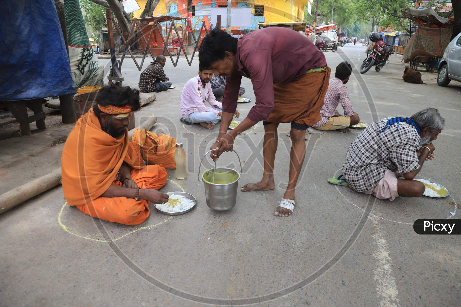 Homeless People Site Inside Circles Drawn On A Road For People To Maintain Safe Distance To Eat Food During A 21-Day Nationwide Lockdown To Slow The Spreading Of Coronavirus Disease (Covid-19) In Prayagraj, April 8, 2020.