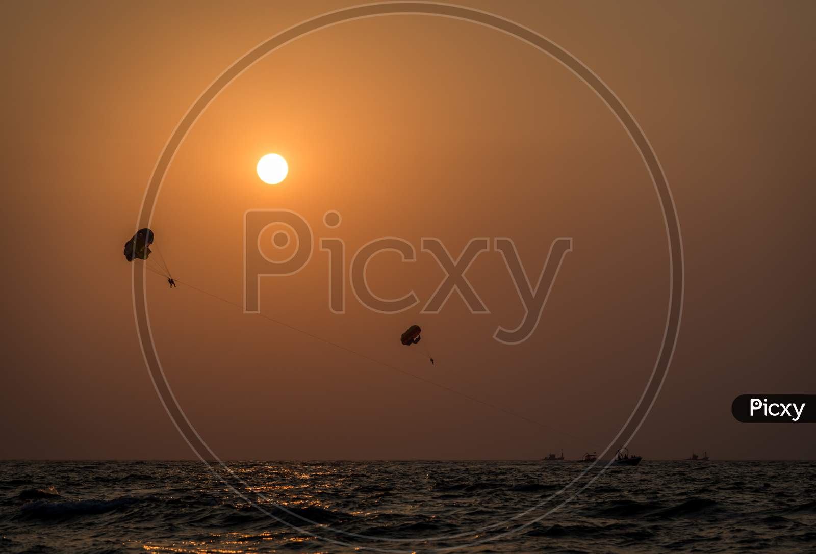 Beautiful wide angle view of a couple parasailing during sunset in the Indian city of Goa