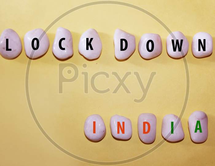 Concept Coronavirus. Lockdown India As A Text With Letters On White Royal Sapphire Rock Pebbles, Template Against A Yellow Background