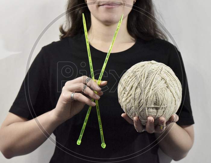 Knitting Needles And The Ball Of Yarn In Hands Of Woman In Black On The White Background. Concept Of Handmade Crafts.