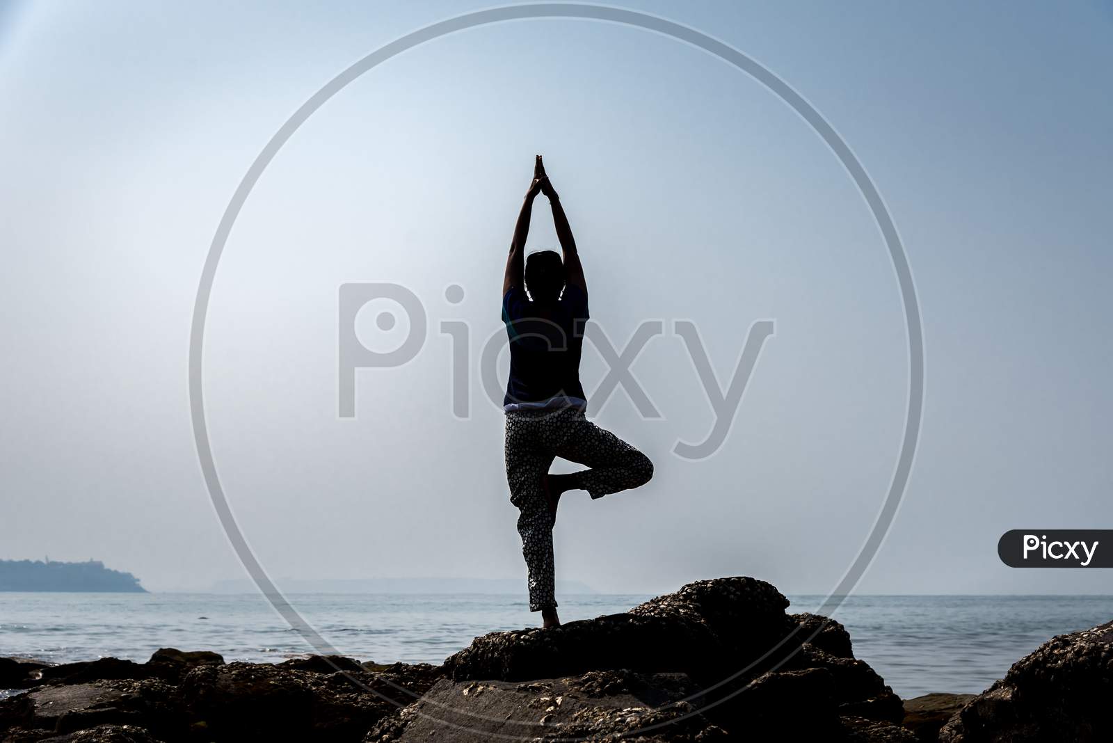 A woman doing yoga in a beach in Goa on a bright sunny day