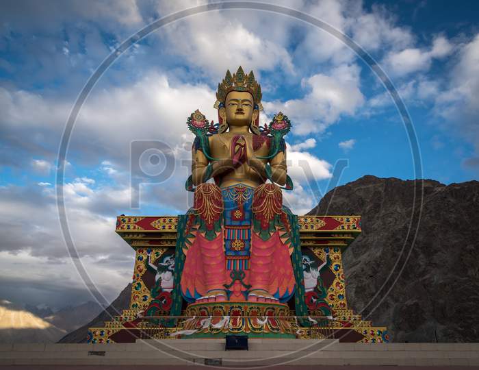 Maitrey Buddha Statue at Diskit Monastery with mountains and sky in the background, Nubra Valley, Ladakh, India