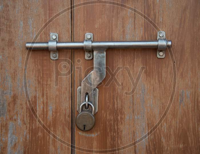 Closeup of a metal latch with a lock on wooden door