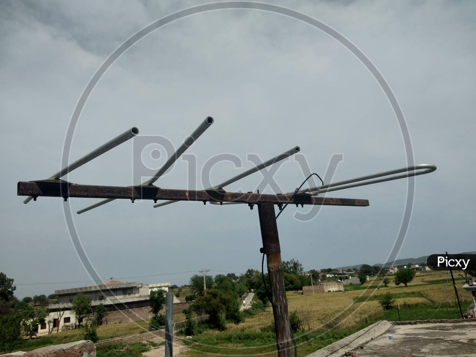 A TV antenna with cloudy sky and village background