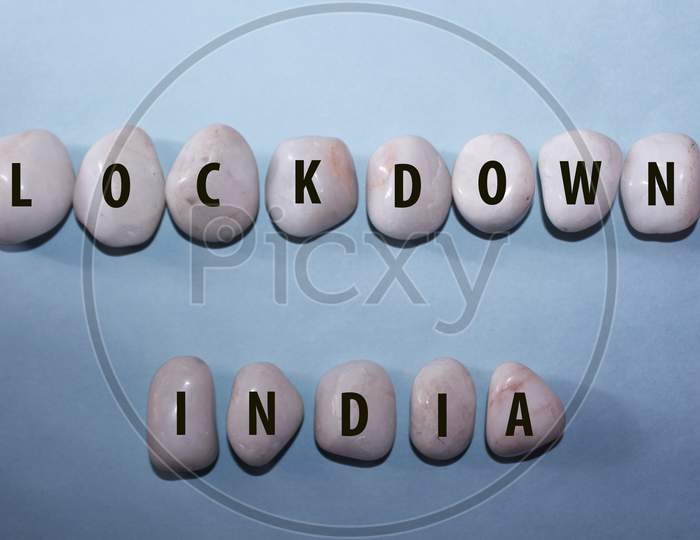 Concept Coronavirus. Lockdown India As A Text With Letters On White Royal Sapphire Rock Pebbles, Template Against A Blue Background