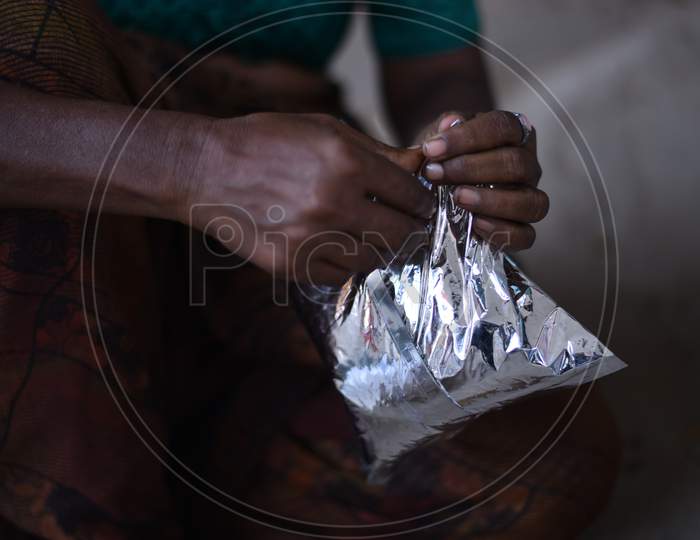 a migrant worker woman opens a food packet  distributed by donors as they couldn't find food and work during nationwide lockdown amid coronavirus pandemic, April 8,2020, Hyderabad.