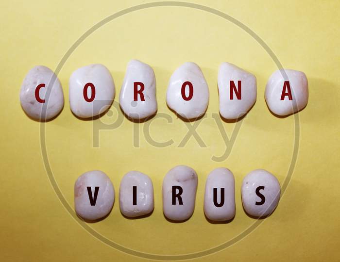 Concept Corona Virus. Corona Virus As A Text With Letters On White Royal Sapphire Rock Pebbles, Template Against A Yellow Background