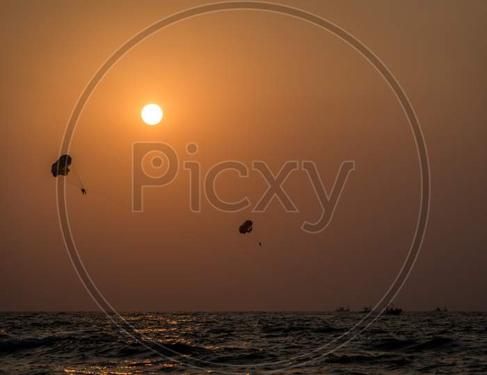 Beautiful wide angle view of a couple parasailing during sunset in the Indian city of Goa