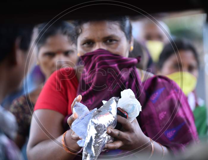 a migrant worker woman collects food packets being distributed by donors as they couldn't find food and work during nationwide lockdown amid coronavirus pandemic, April 8,2020, Hyderabad.