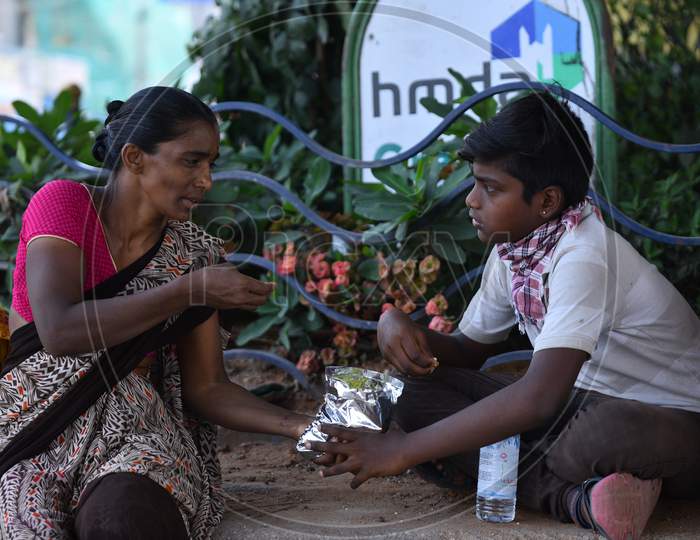 a migrant worker woman shares food with her son that is distributed by donors during nationwide lockdown amid coronavirus pandemic, April 8,2020, Hyderabad.