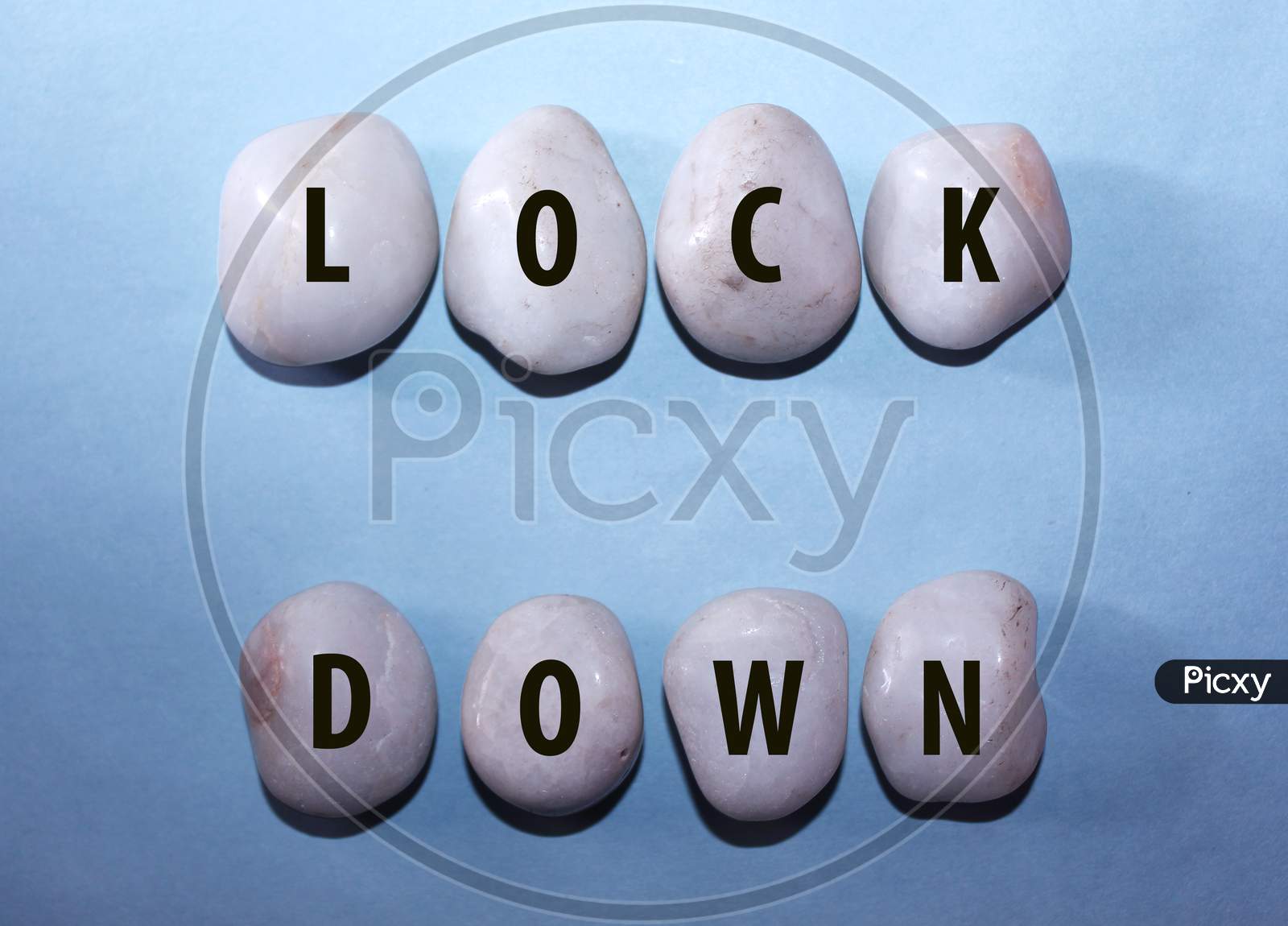 Concept Coronavirus. Lock Down As A Text With Letters On White Royal Sapphire Rock Pebbles, Template Against A Blue Background