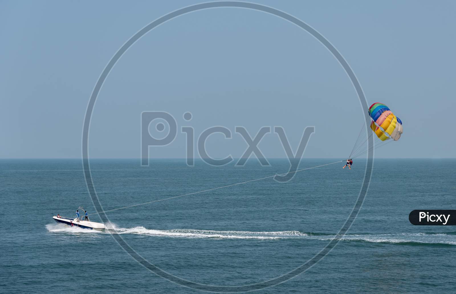 Beautiful wide angle view of a Couple parasailing over a beach on a sunny day