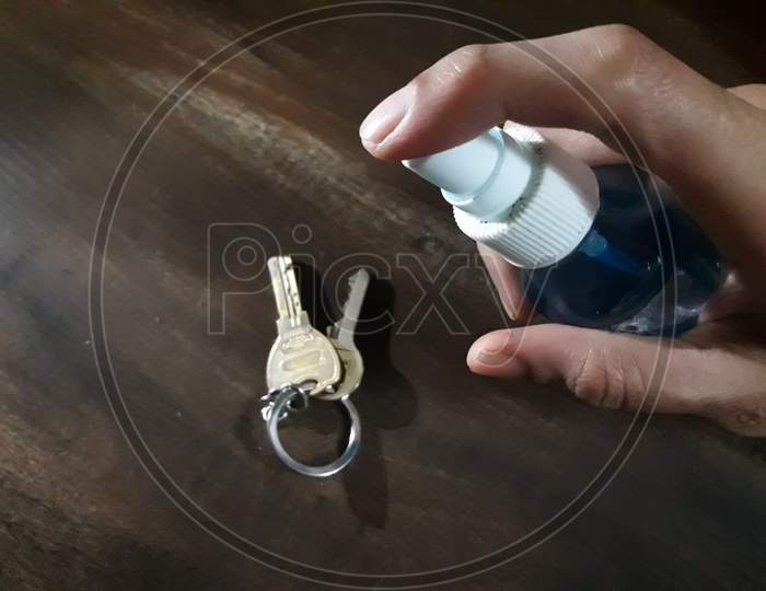 Disinfecting The Keys With Sanitizer On A Wooden Table to avoid the spread of coronavirus or covid 19