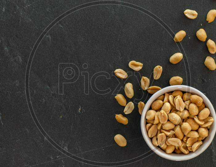 bowl with roasted and salted peanuts on a slate with copy space