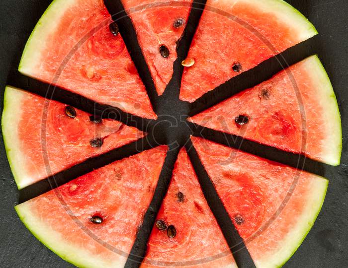 pieces of water melon arranged in circle on black