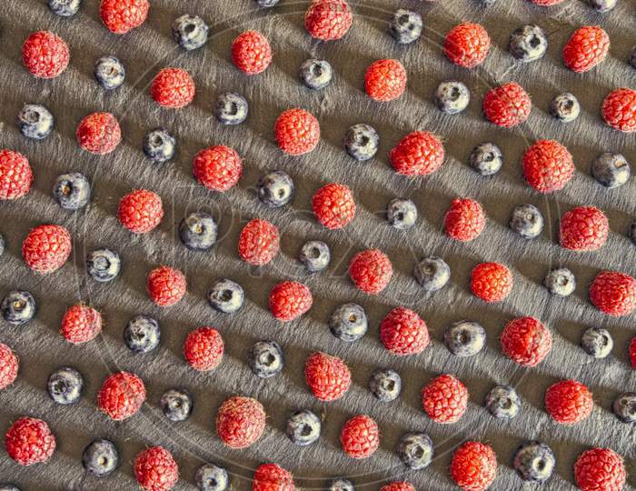 close up of raspberries and blueberries arranged as a pattern