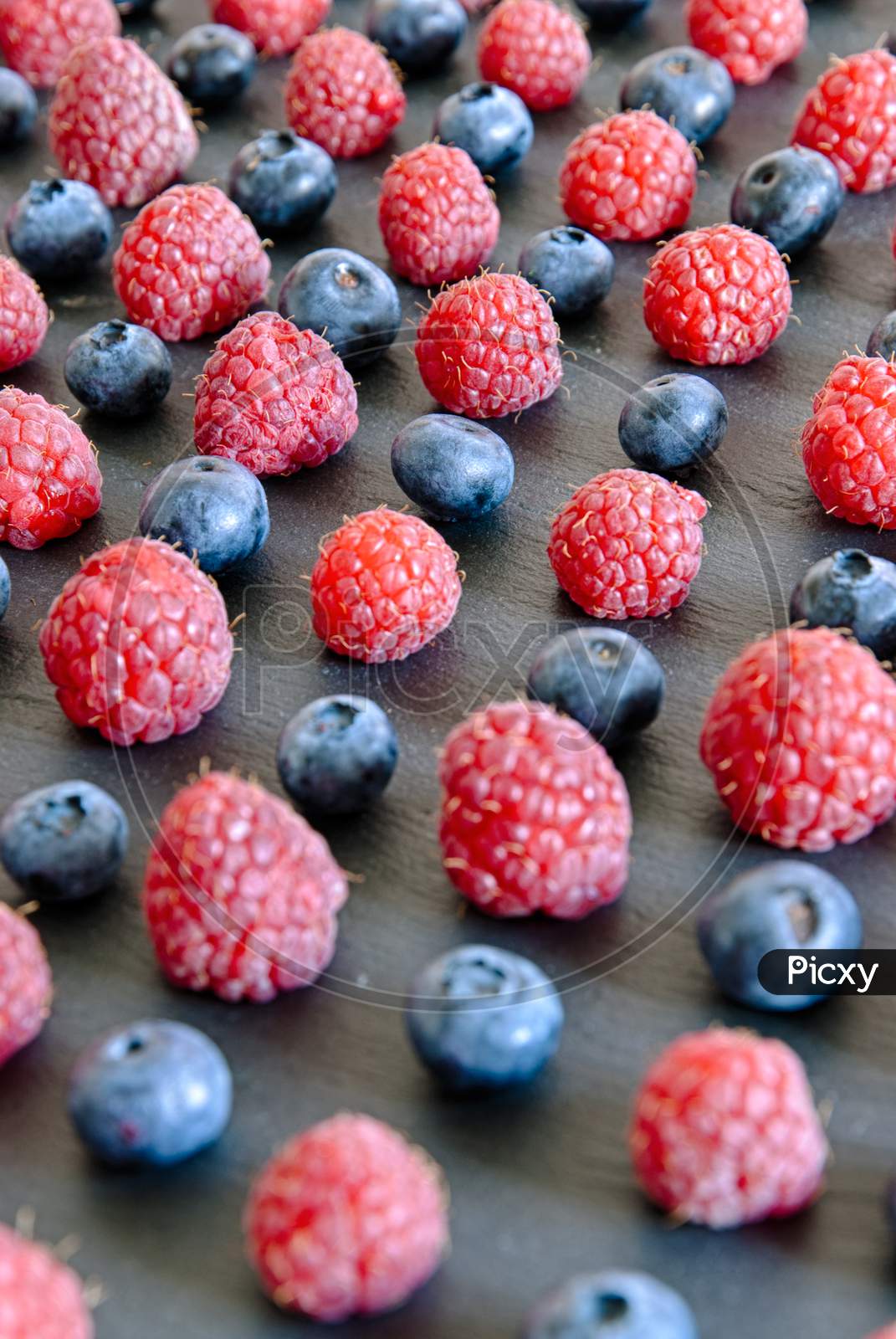 close up on raspberries and blueberries arranged as a pattern