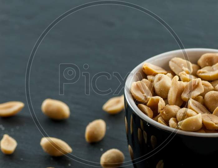 bowl with roasted and salted peanuts on a slate with copy space