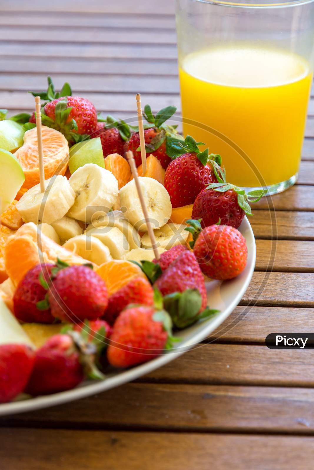 plate with assortment of fruit slices on a wooden table and glass with fresh orange juice healthy eating concept