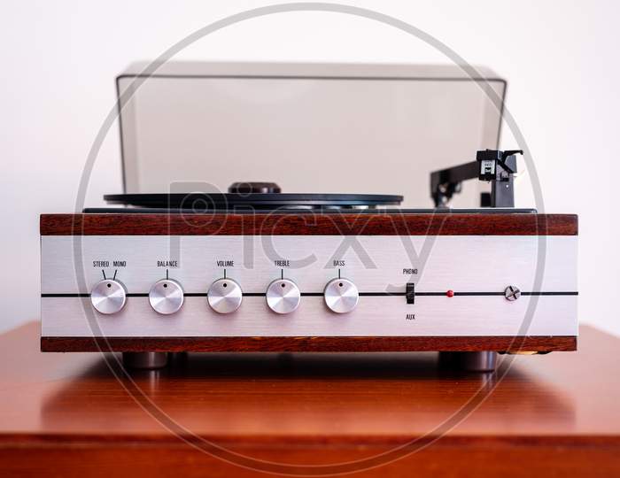 Vintage turntable made of wood and plastic cover on an old table