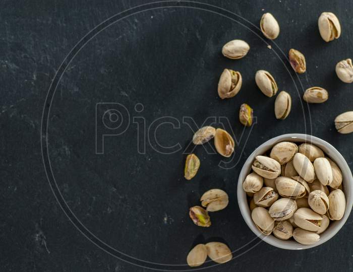 bowl with roasted pistachio on a black slate with copy space