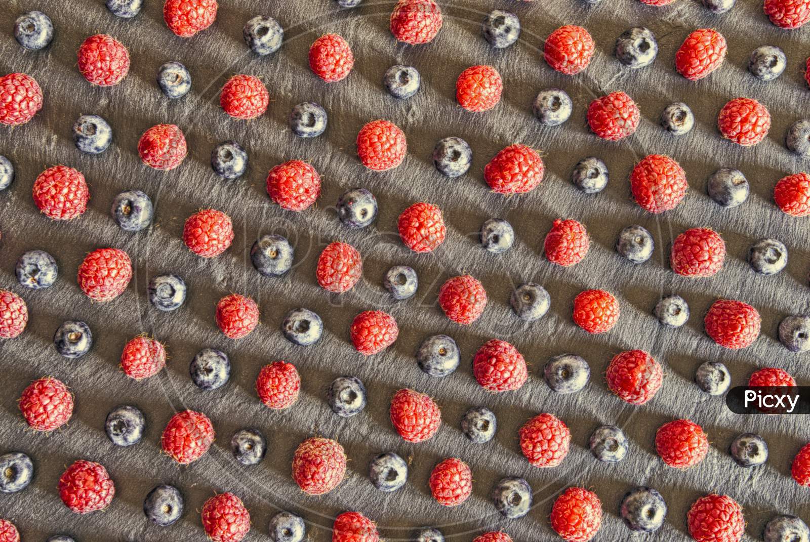 close up of raspberries and blueberries arranged as a pattern