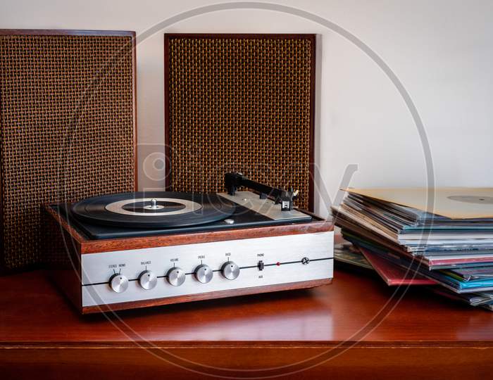 Vintage turntable made of wood with speakers and vinyls on an old table