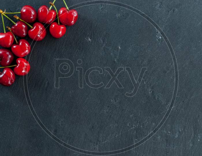 cherries arranged as a frame on black with copy space