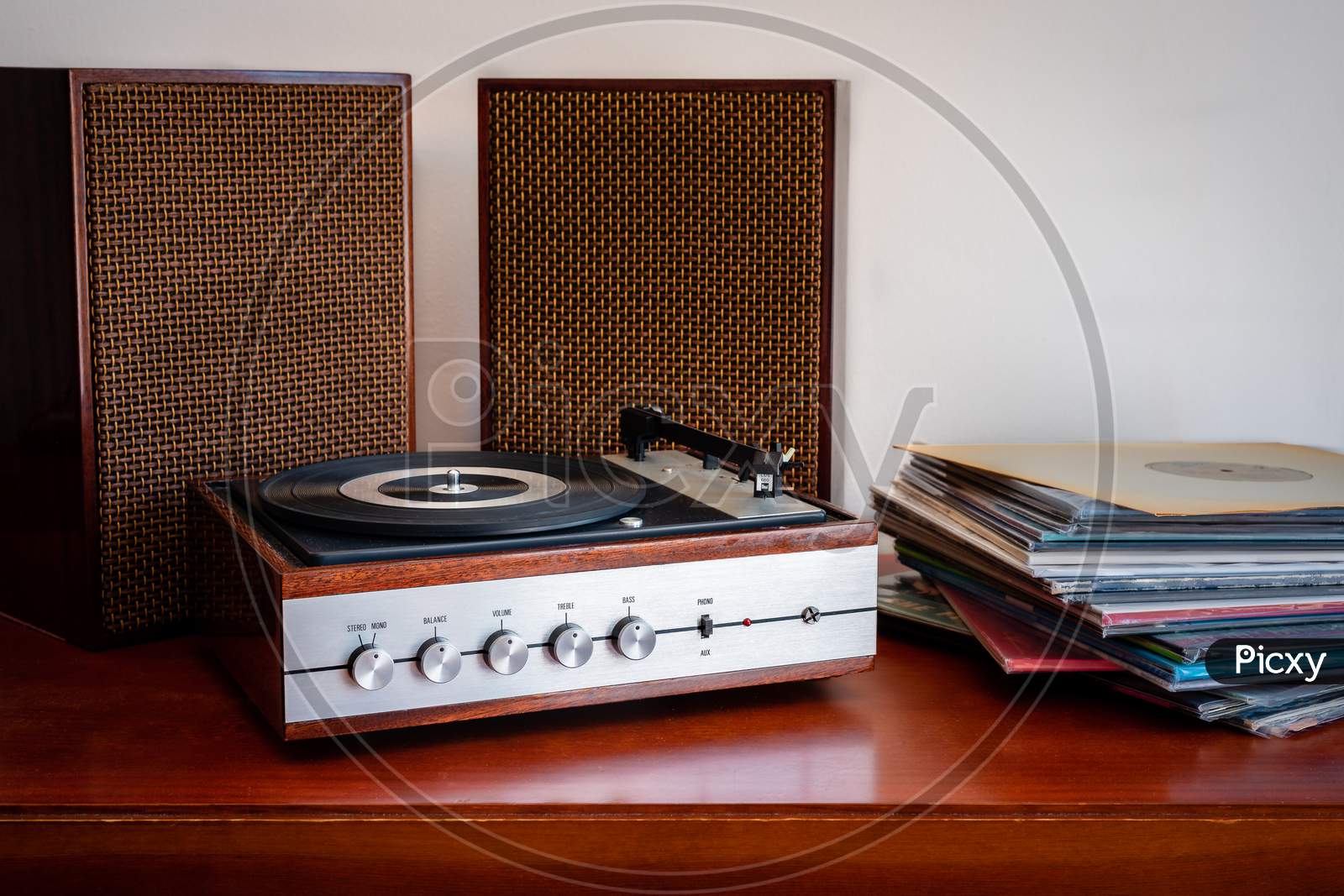Vintage turntable made of wood with speakers and vinyls on an old table
