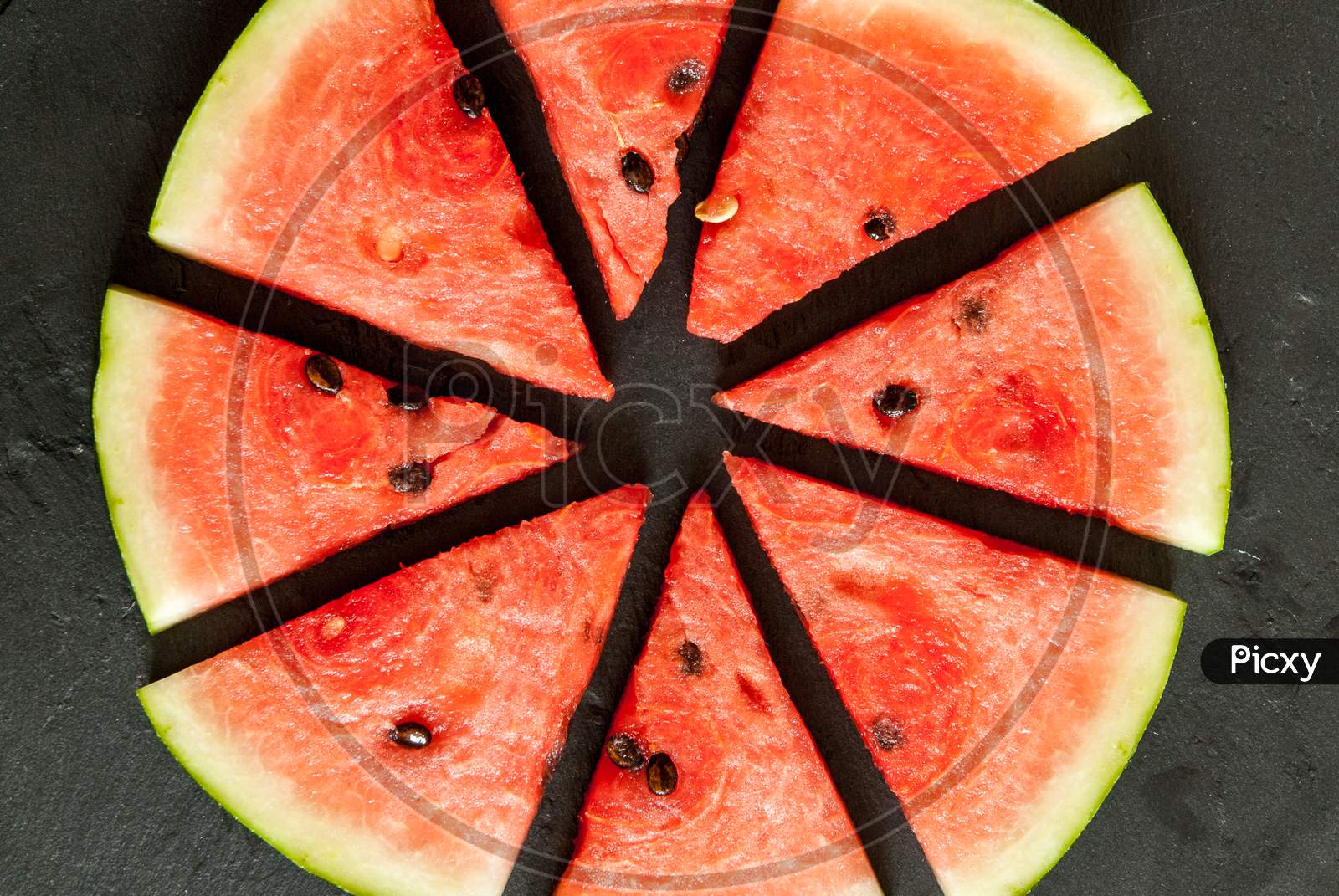 pieces of water melon arranged in circle on black