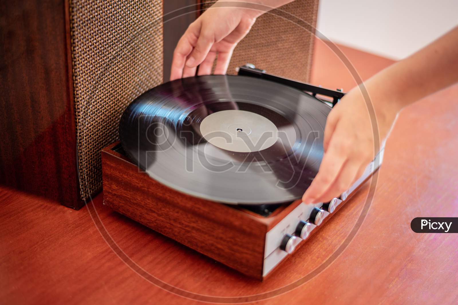 Hands put a vinyl on an old wooden turntable