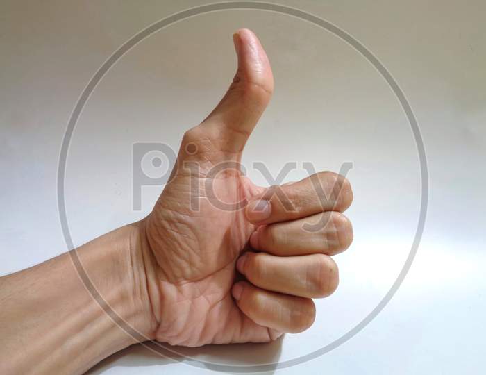 Close up shot of a male hand showing thumbs up on white background