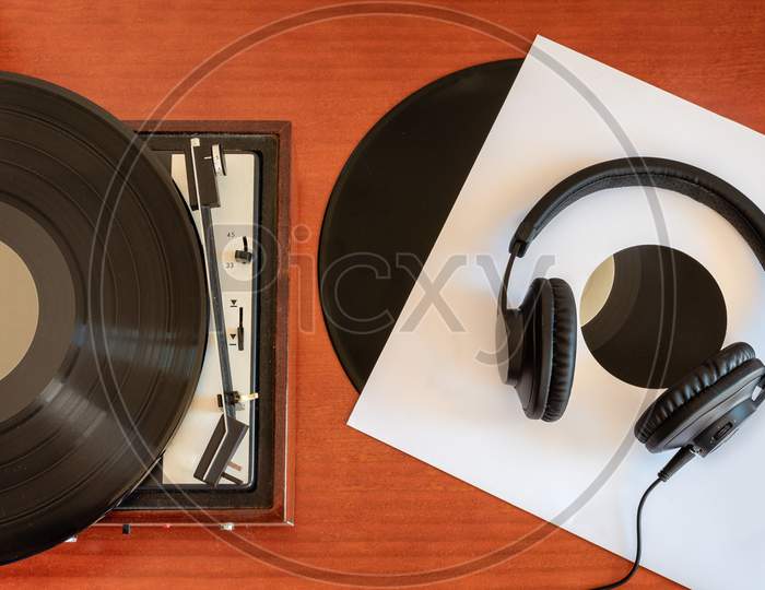 Vintage turntable made of wood with vinyls and headphones on an old table