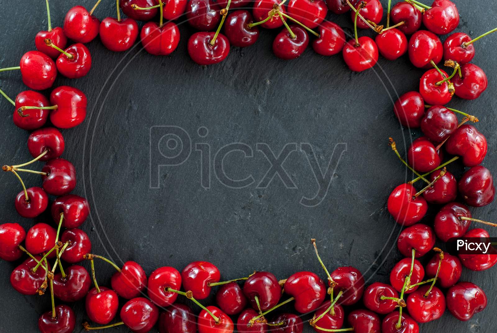 cherries arranged as a frame on black with copy space