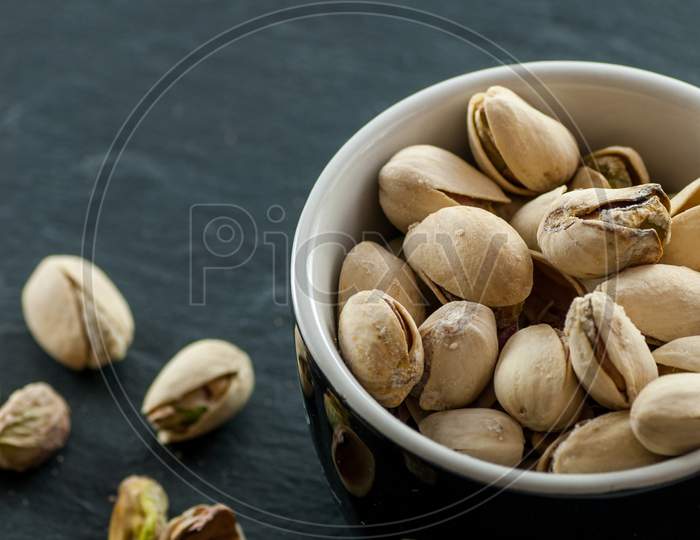 bowl with roasted pistachio on a black slate with copy space