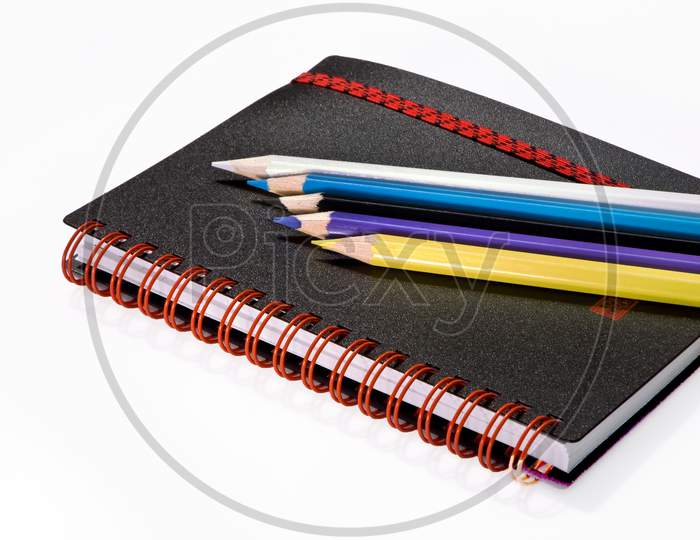 A note book with colour pencils