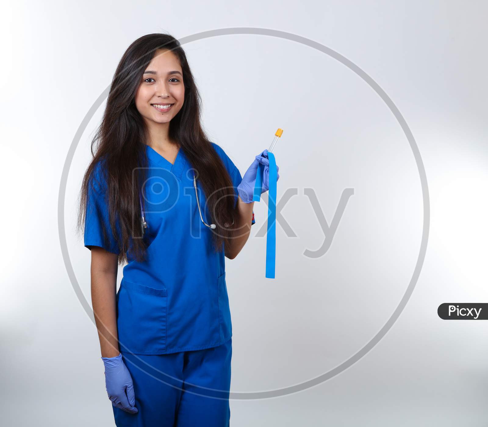 A Young Nurse In Blue Scrubs Stands Ready To Take A Blood Test.