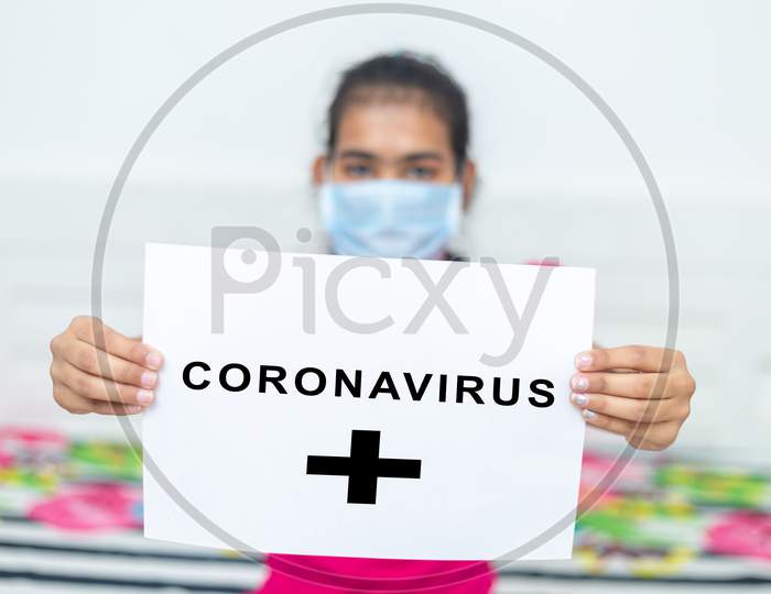 Young Girl Wearing Surgical Protection Mask Holding White Board With Text Coronavirus During Quarantine. Stay At Home Concept.