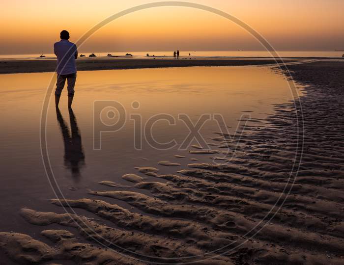 Sillhoute of an unrecognizable man during sunset in the beach of Oman.
