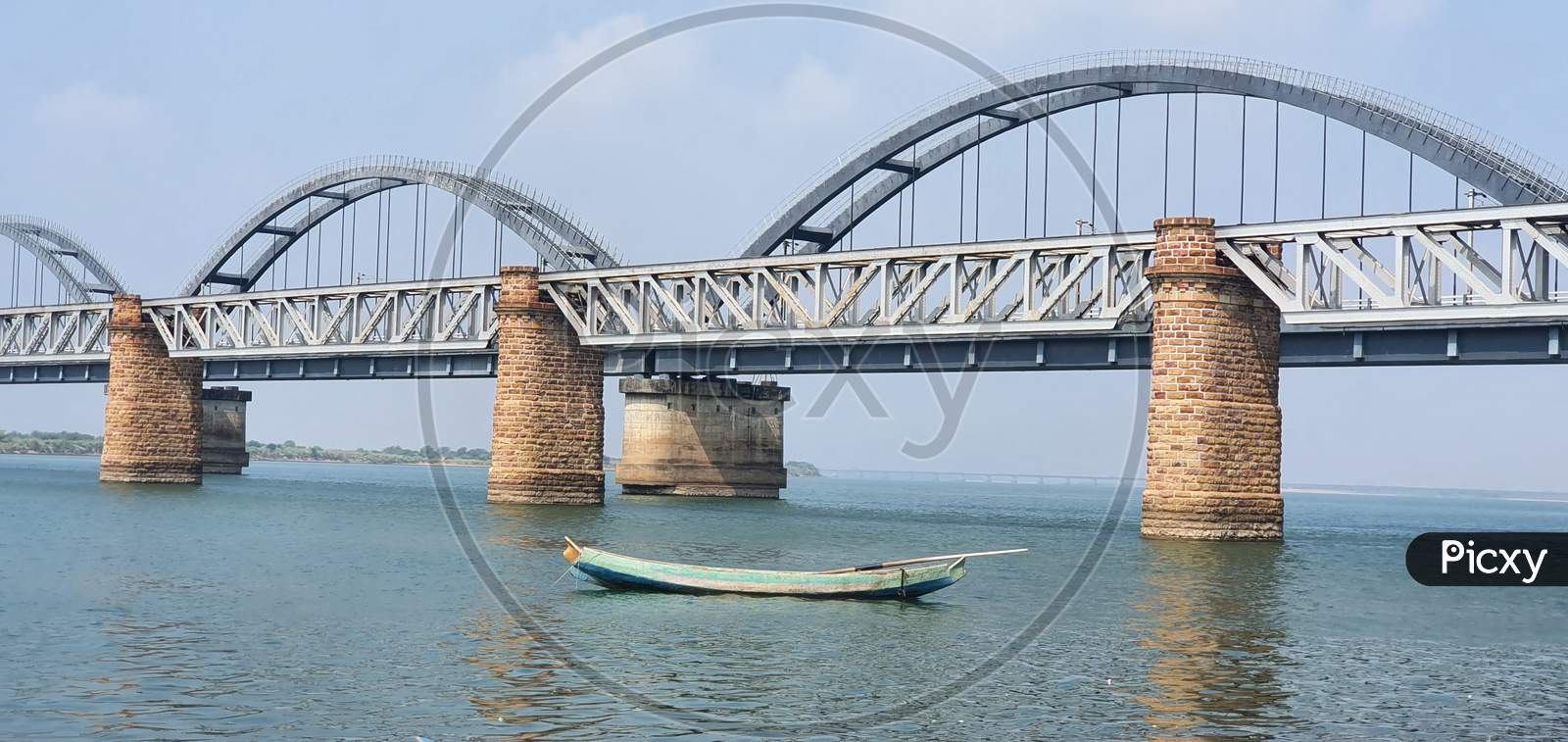 Fishing boat against the backdrop of railway bridges on Godavari river