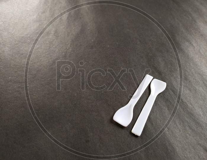 Small white spoons on black background.