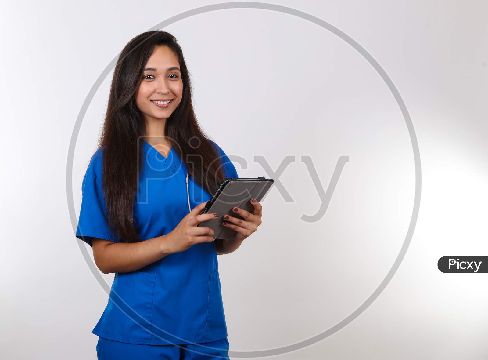 An Attractive Female Nurse Takes Notes On Her Tablet.