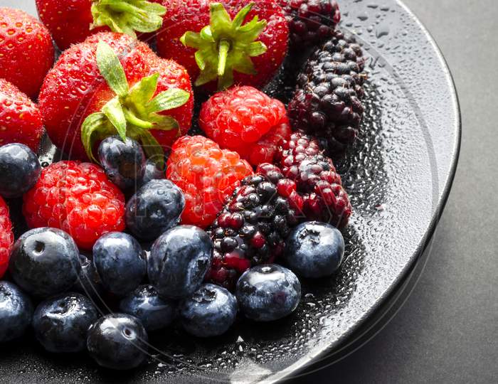 A horizontal shot of a plate of fresh summer fruit.