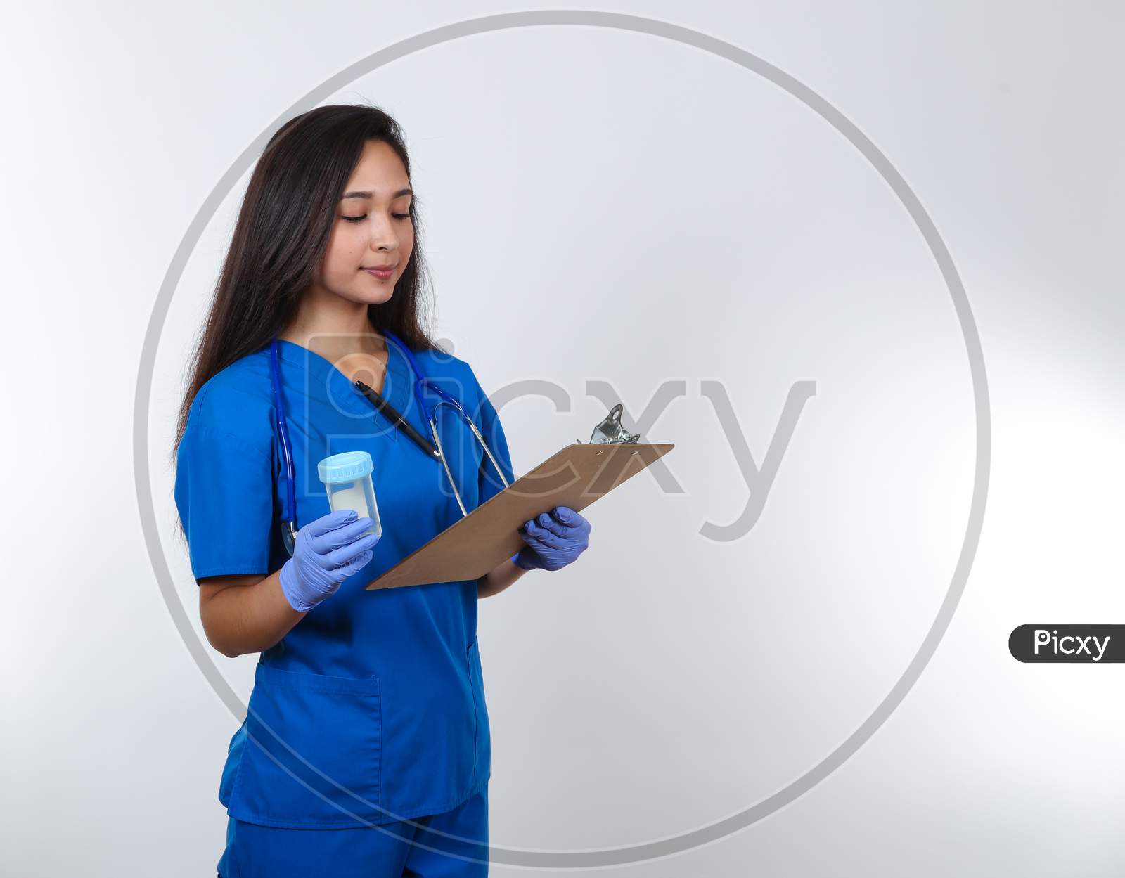 A Young Female Nurse In Blue Scrubs Prepares To Administer A Drug Test.