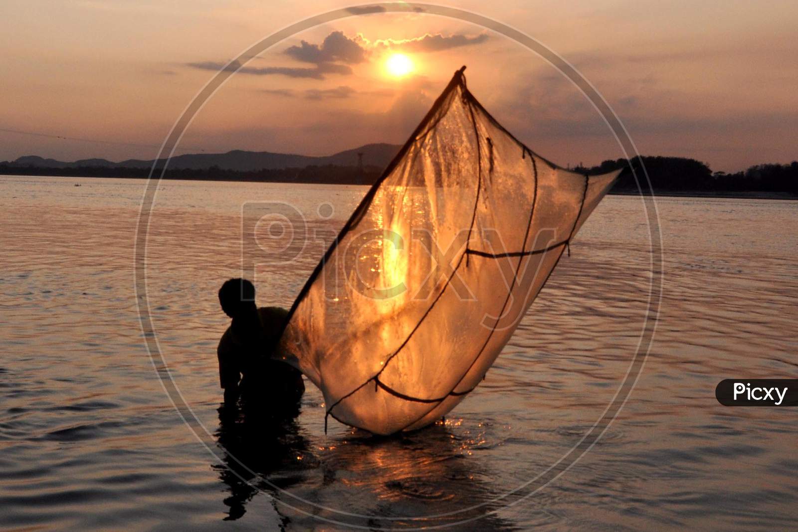 A Man Catches Fish At The Banks Of The Brahmaputra River During Sunset  In Guwahati, Saturday, May 9, 2020.