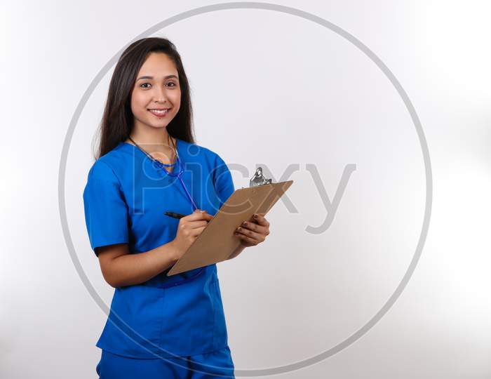 A Pretty Hispanic Nurse Takes Notes On Her Clipboard.