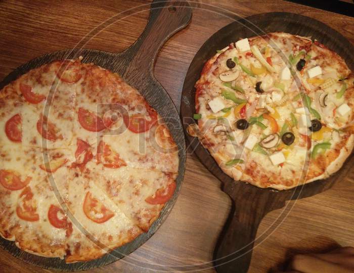Pair of pizzas with tomato toppings and panner olive