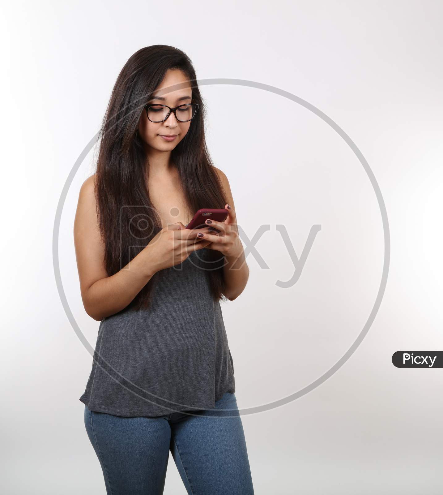 A Pretty Young Girl Wearing Glasses Is Distracted; Looking At Her Phone.