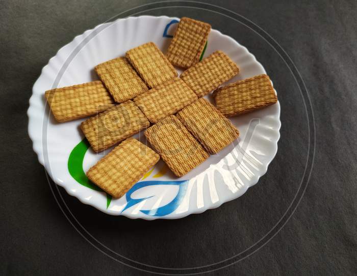 Healthy biscuits on plate, black background.